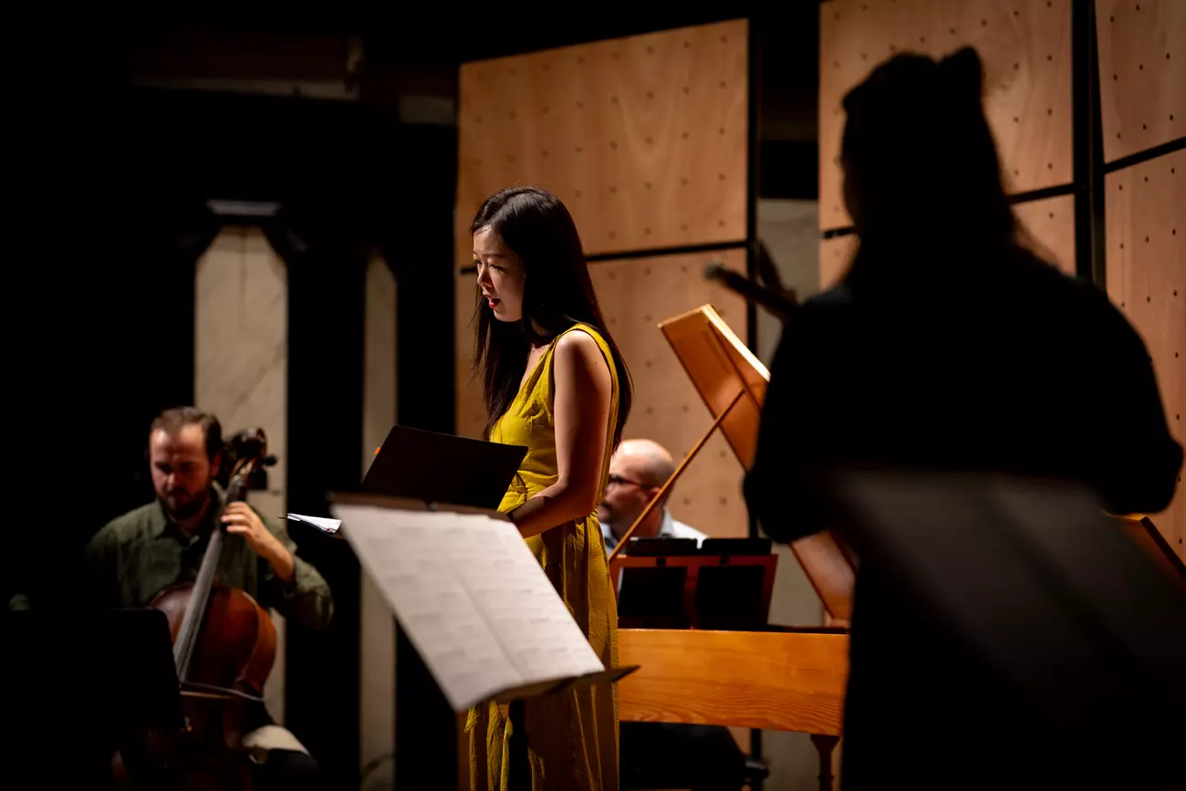 Performance of ensemble during the festival. Woman in yellow singing from sheet music.