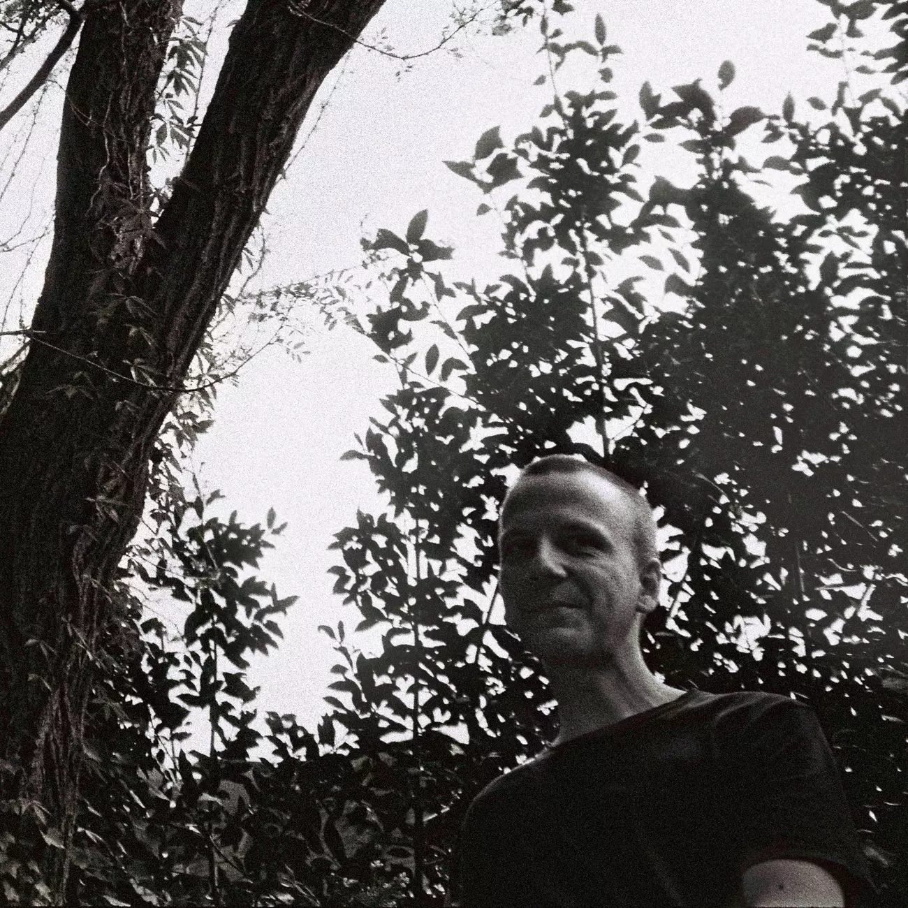 Lars Tuchel standing in front of a tree and smiling.